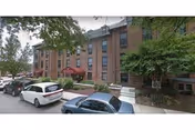Exterior view of Kentmere Rehabilitation and Healthcare Center with parked cars and trees.