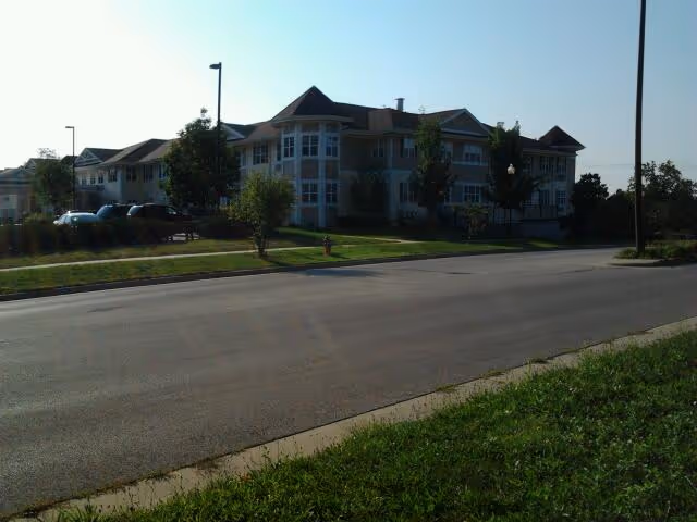 Exterior view of Victorian Woods senior living facility along a street with landscaping