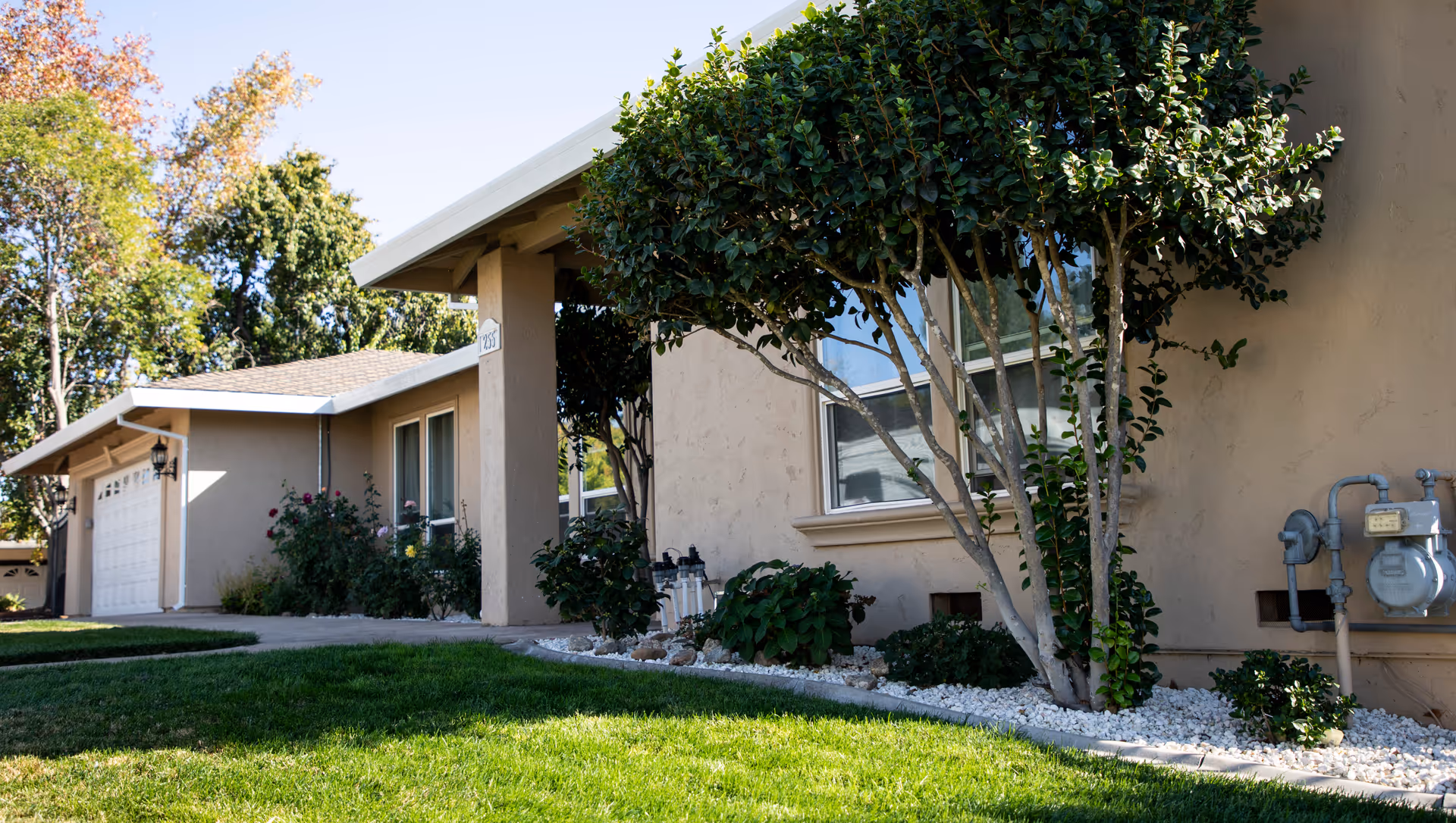 Beige, single-story senior care building with a manicured lawn and landscaped front yard.