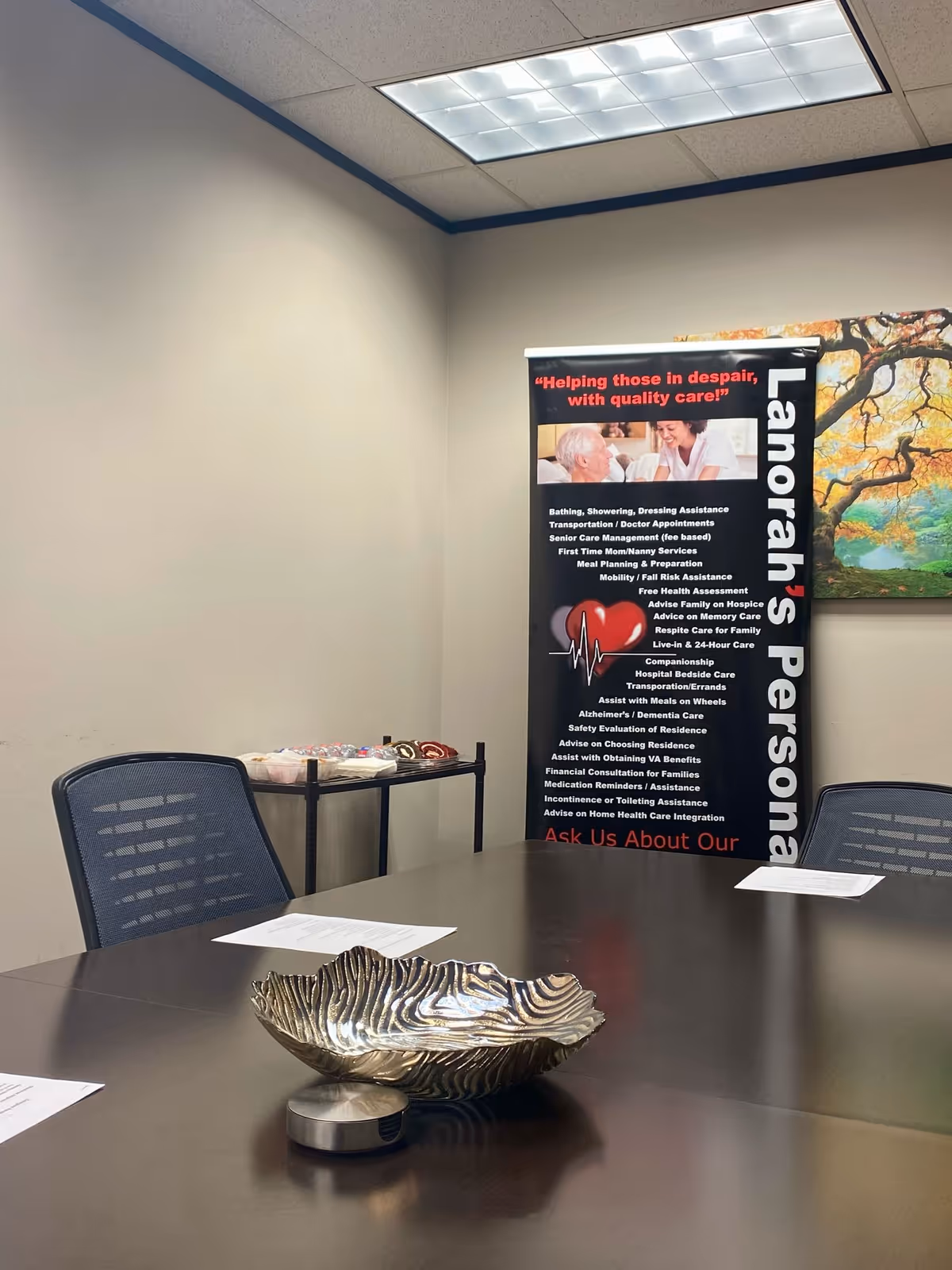 Interior conference room with a Lanorah's Personal Care banner next to a table centerpiece.