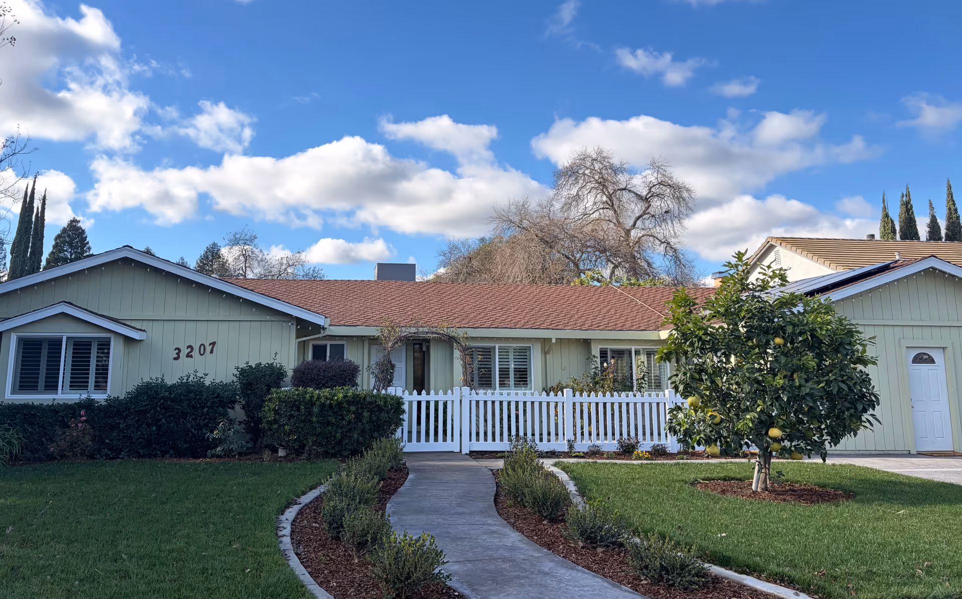 Isabella's Residential Care Home exterior: single-story green house with white picket fence.
