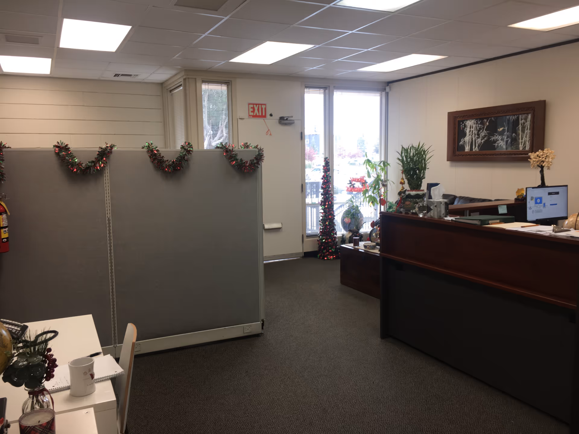 Office reception area with grey partition dividers, holiday garlands, and a front desk.