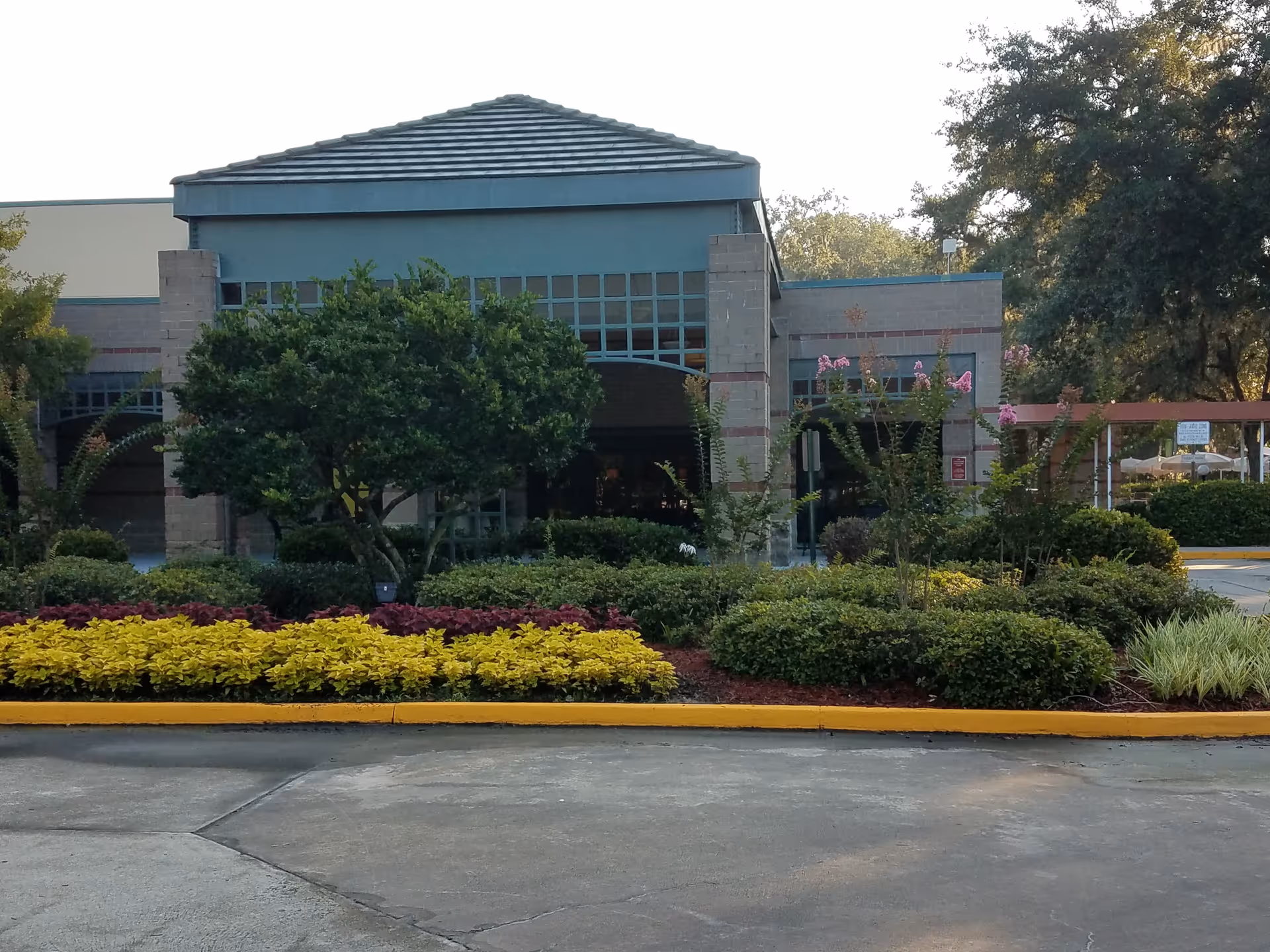 Front exterior of River Garden Hebrew Home for the Aged with landscaped bushes and trees.