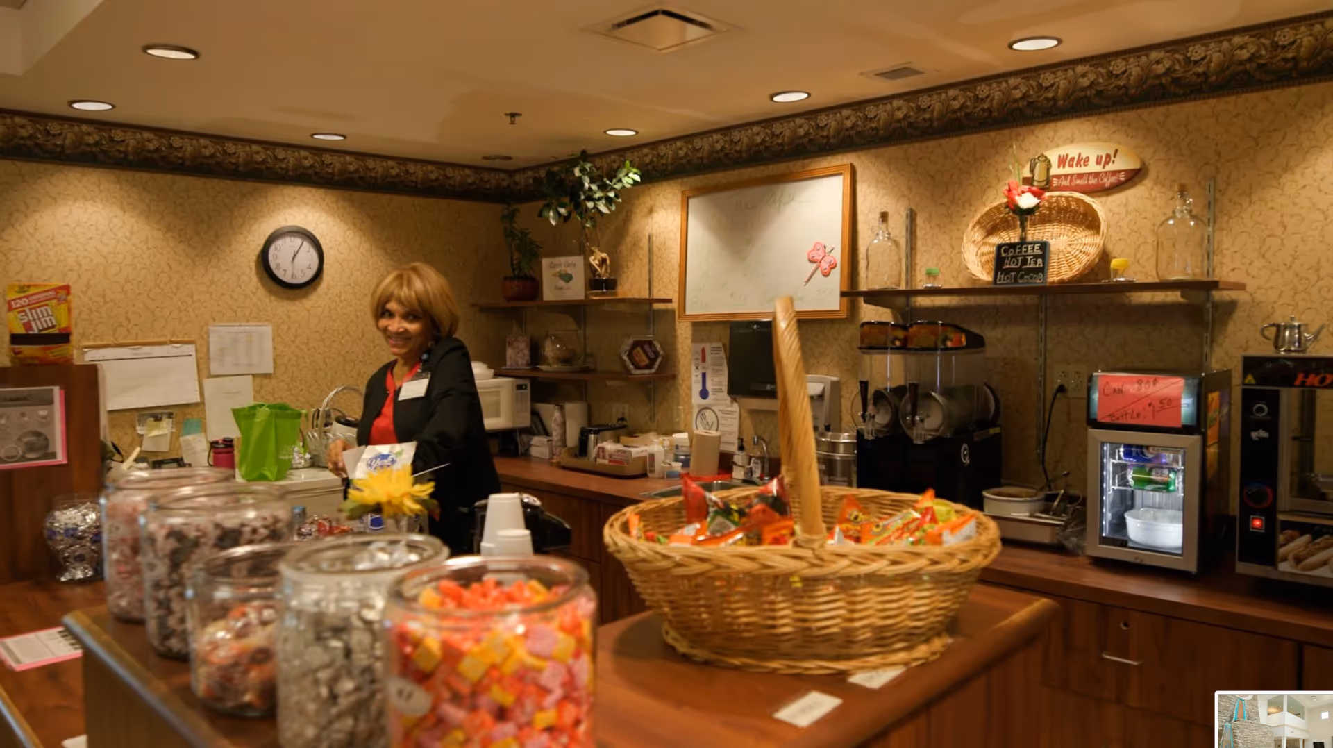 Staff member behind a service counter with candy jars in a cozy assisted living lounge.