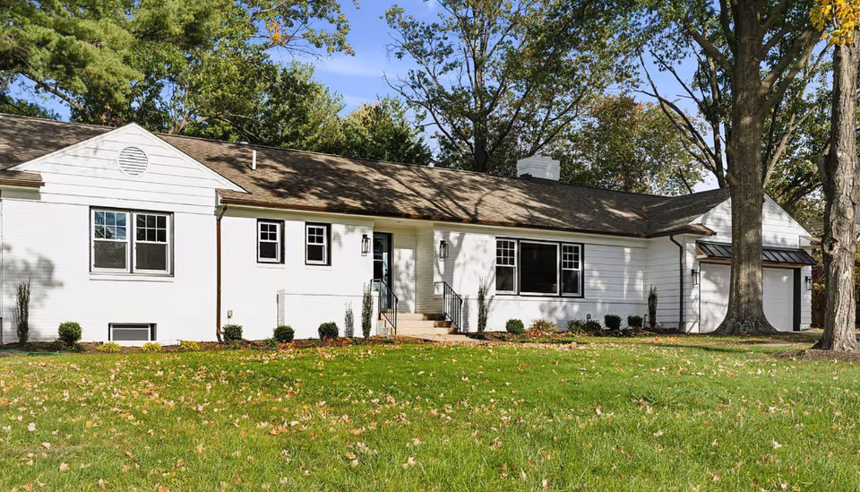 White single-story senior living facility with a manicured front lawn and large windows.