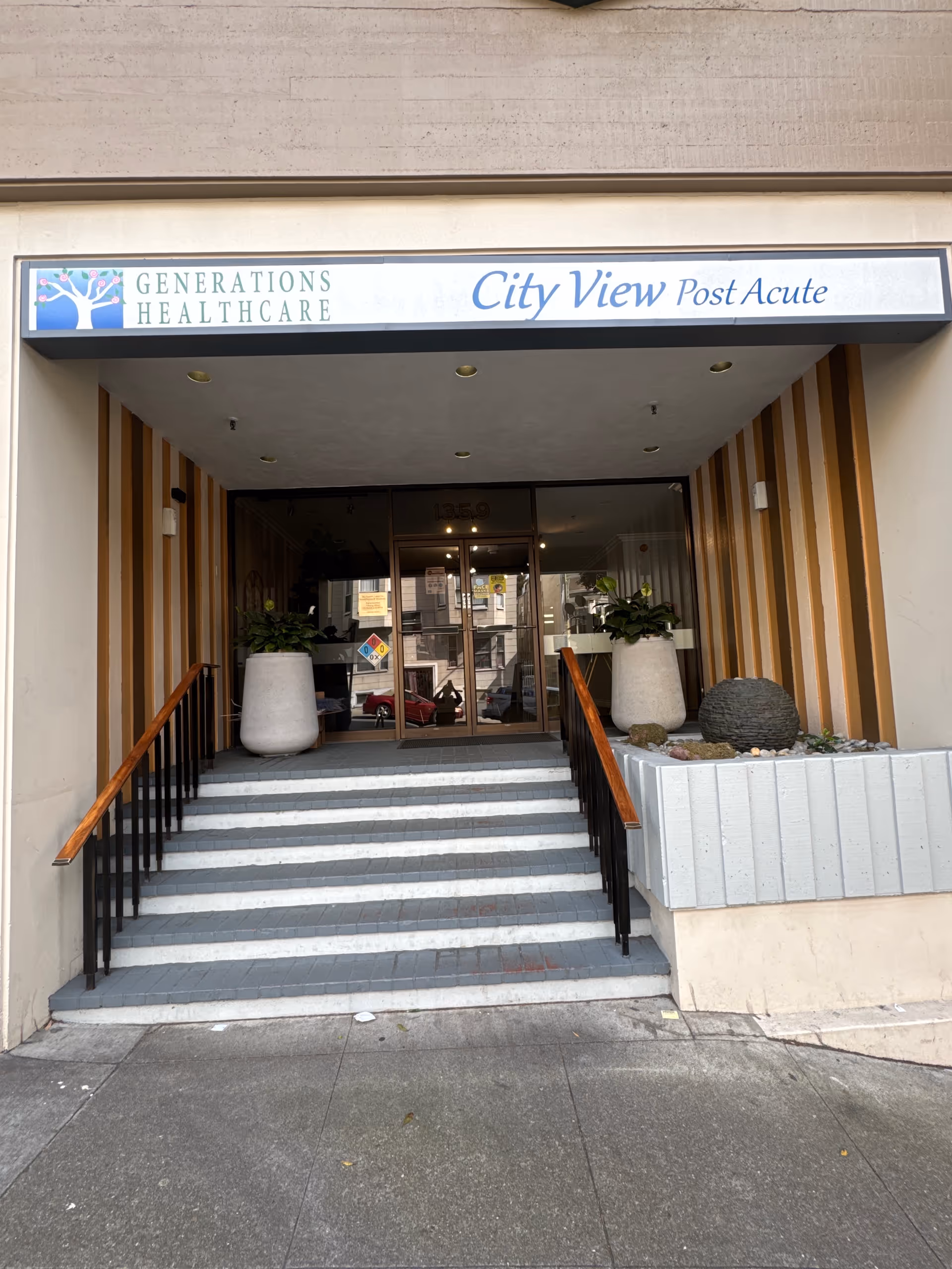 Front entrance of City View Post Acute with stairs, glass doors, and planters.