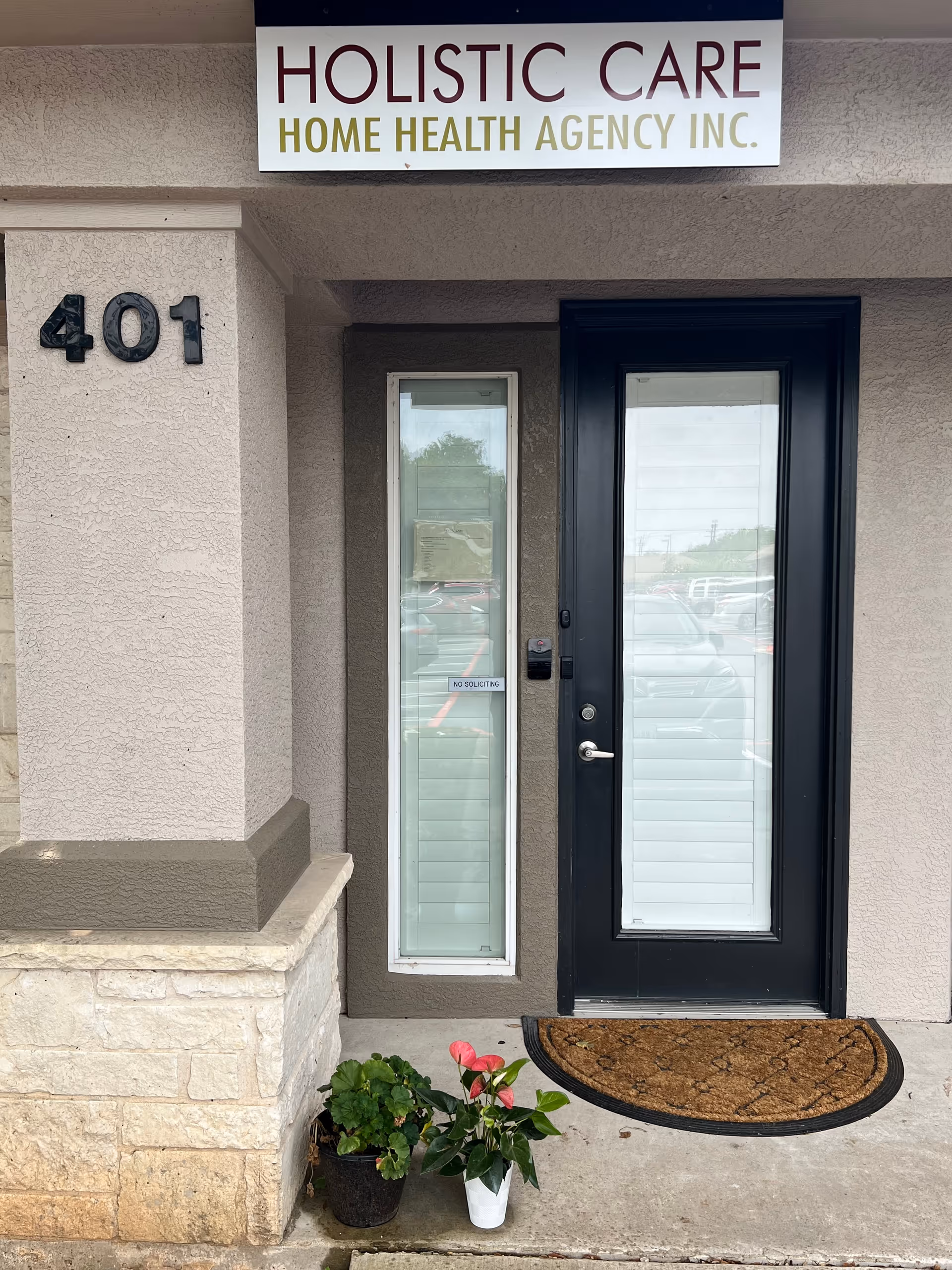 Exterior view of Holistic Care Home Health Agency entrance with address 401 and potted plants.