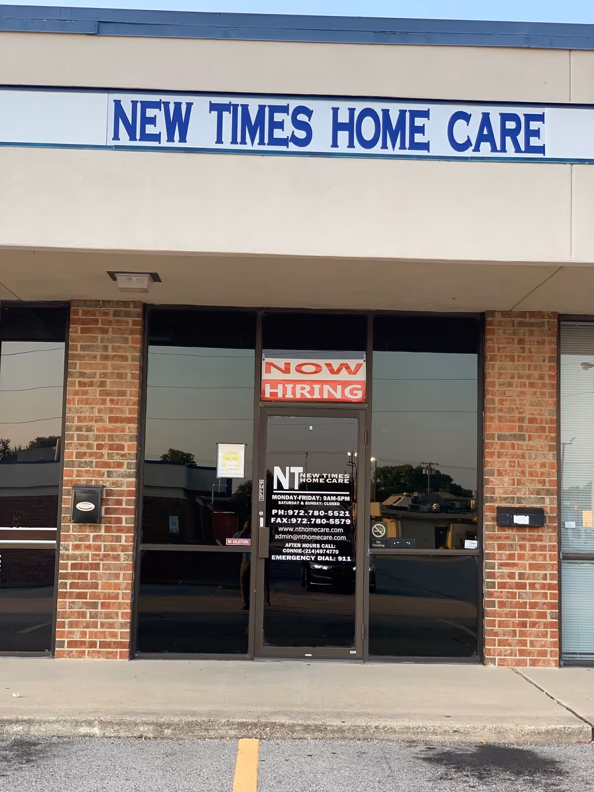 Front of New Times Home Care building with glass doors and Now Hiring sign.