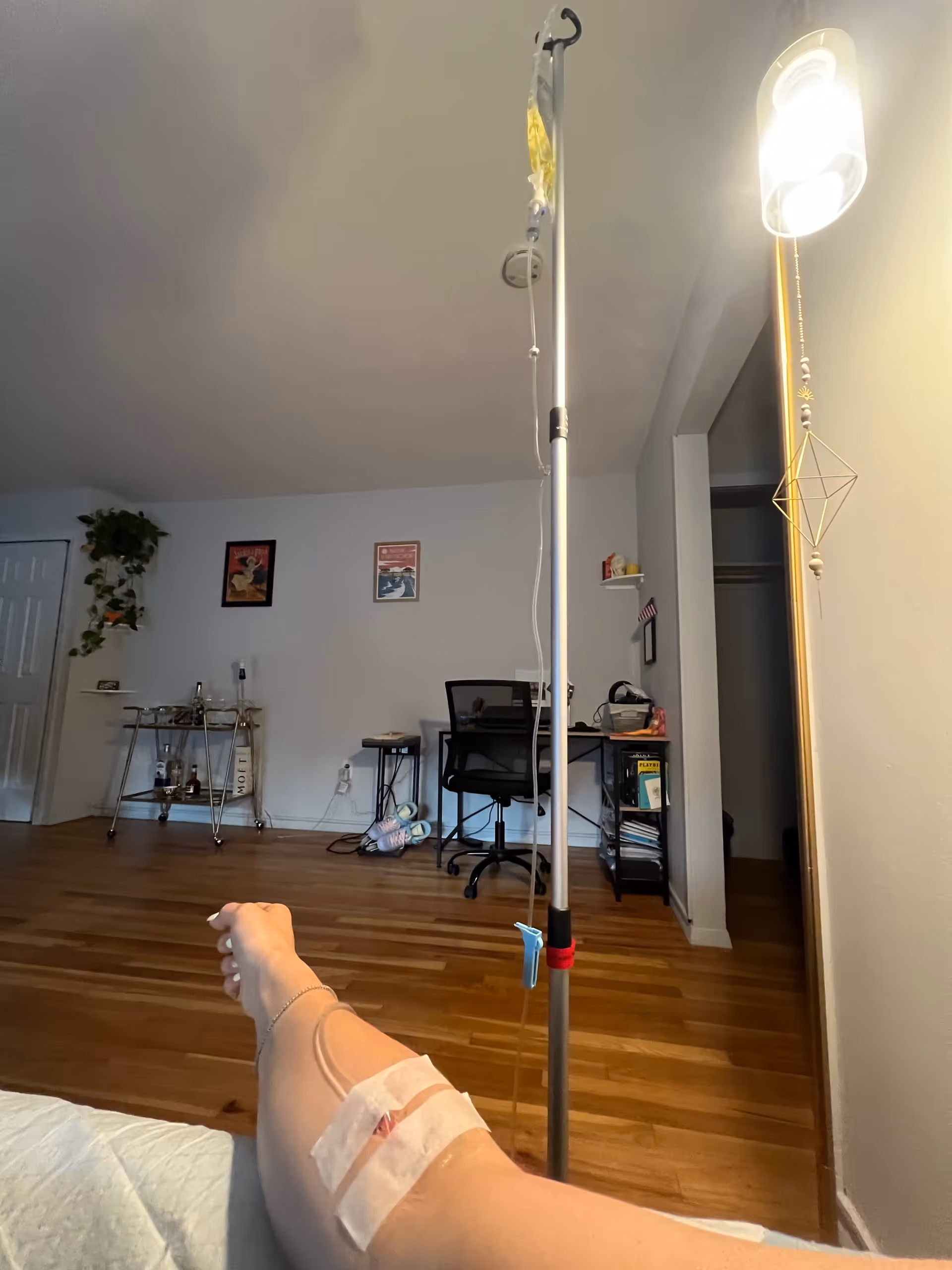 IV pole with tubing and a leg with a bandage in a home living room