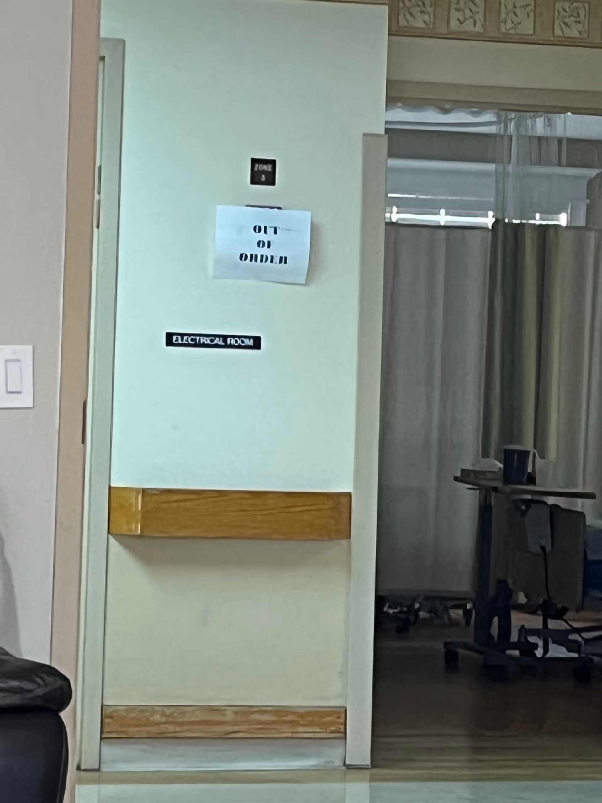 Interior hallway with an Electrical Room door, Out of Order sign, and medical cart.