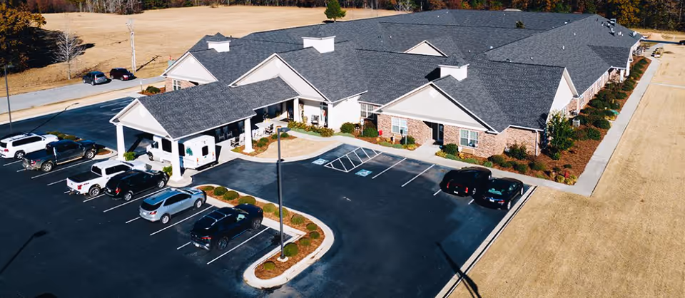 Aerial view of Grand Manor senior living facility with parking and entrance.