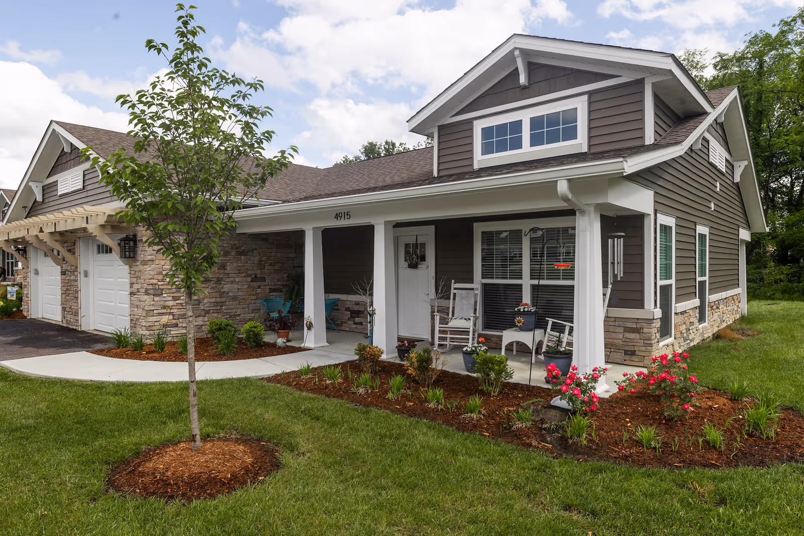 Front exterior of Rivercrest Senior Living with porch seating and landscaped yard.