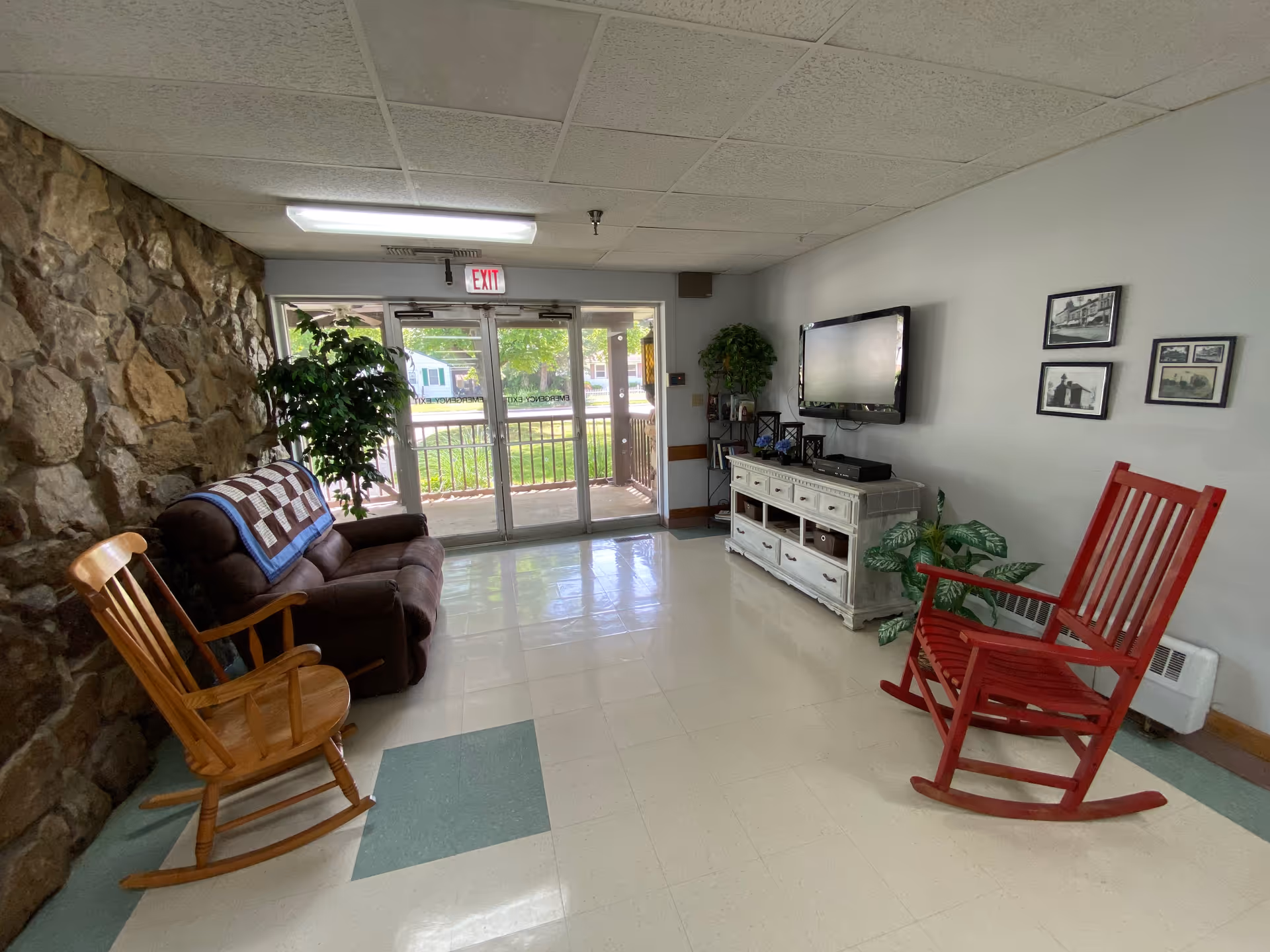 Cozy living room/lounge at Golden LivingCenter LaPorte with stone wall and glass doors.