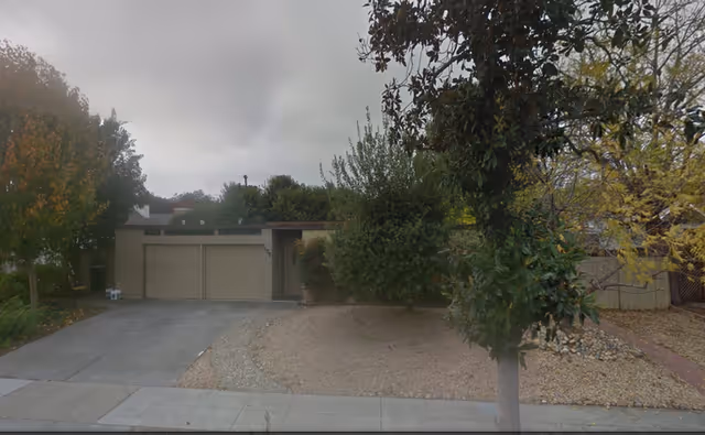 Street view of a beige senior living facility front with a driveway and trees