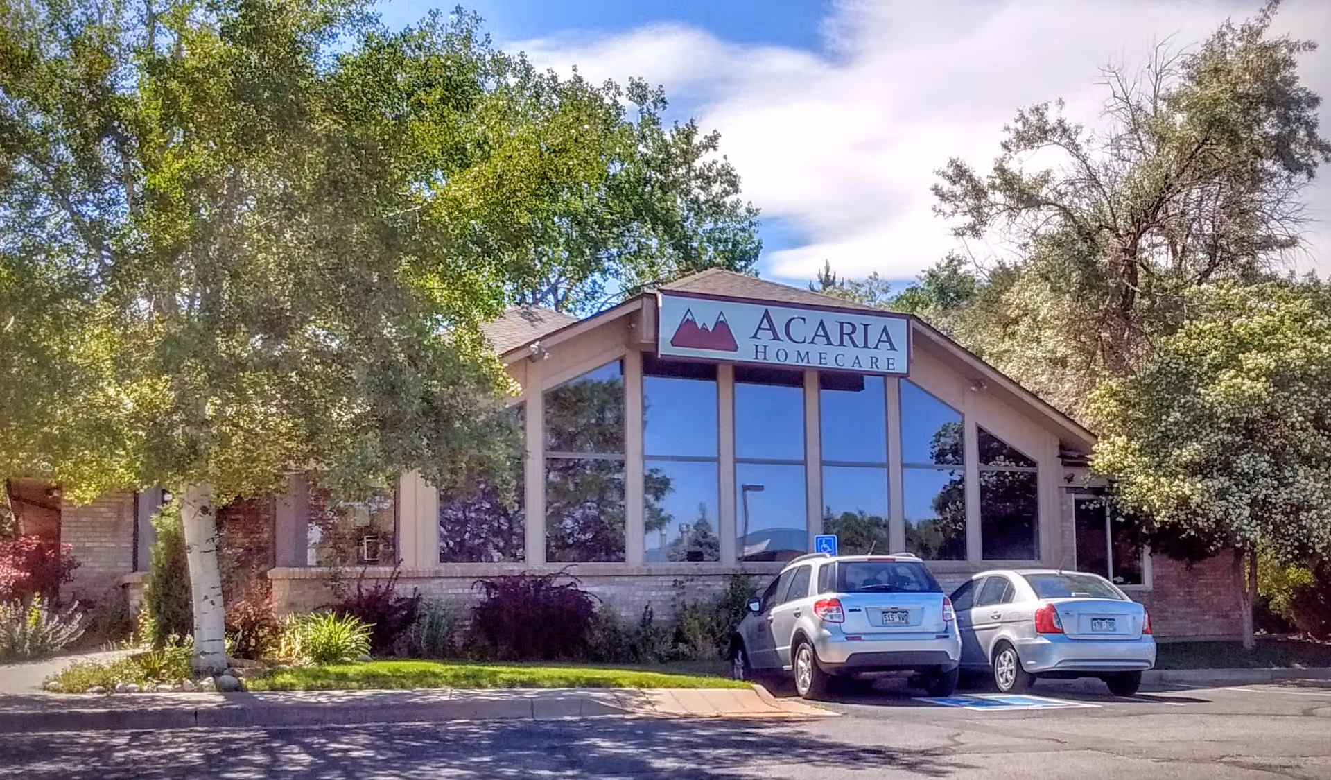 Front of Acaria Homecare facility with glass windows and parked cars.