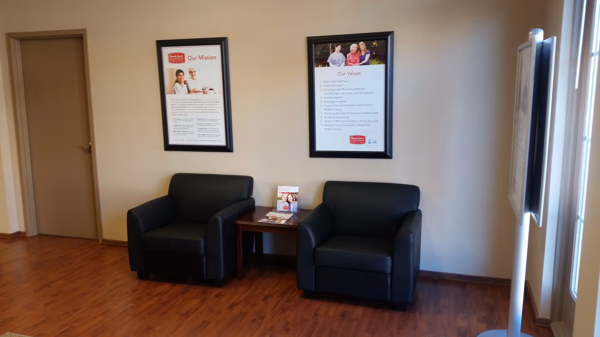 Waiting area with two black armchairs, a small table, and framed posters.