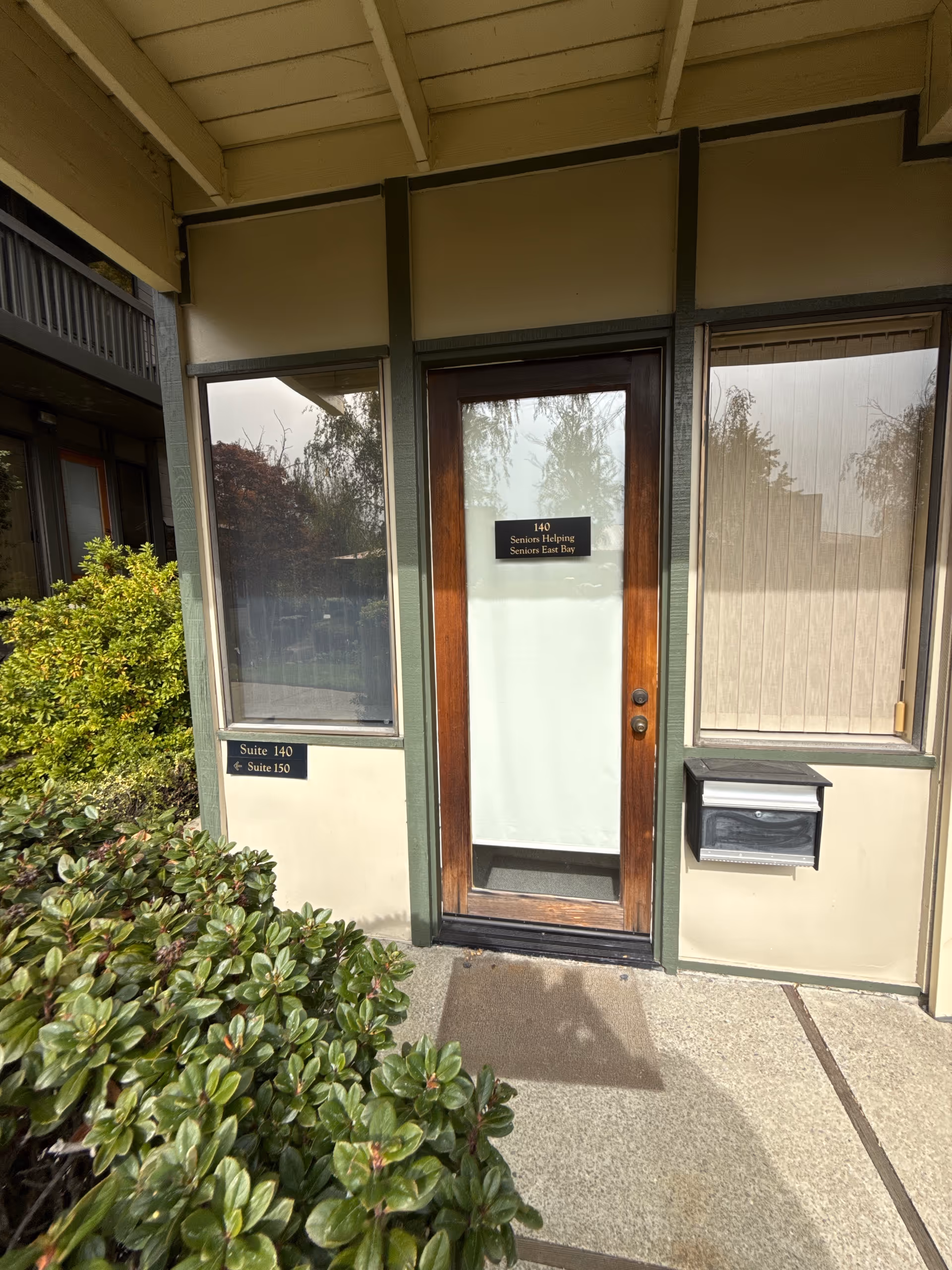 Exterior entrance of Seniors Helping Seniors East Bay with glass door, plants, and signage.