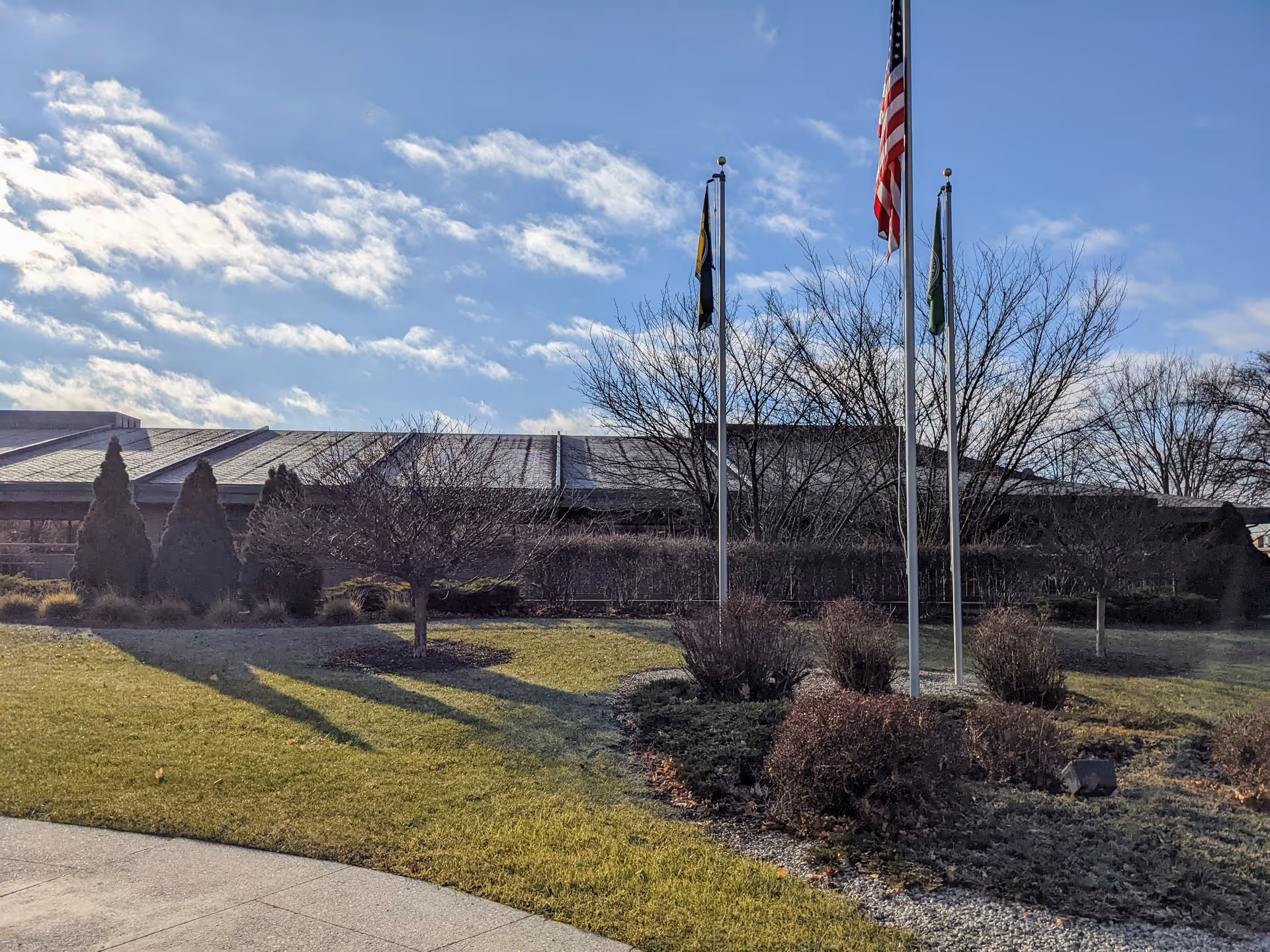 Exterior view of Castle Hospice building with flagpoles, bare trees, and manicured landscaping.