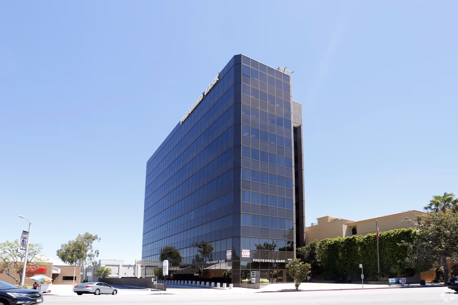 Tall blue-glass office building against a clear sky.