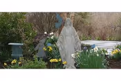 Outdoor garden with blooming flowers surrounding a religious statue.