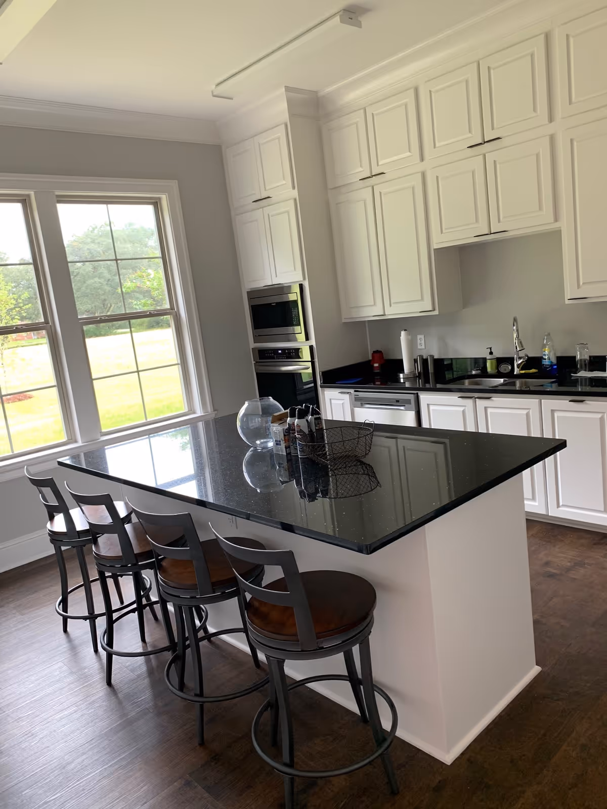 Bright modern kitchen with white cabinets, black granite island, and stainless appliances.
