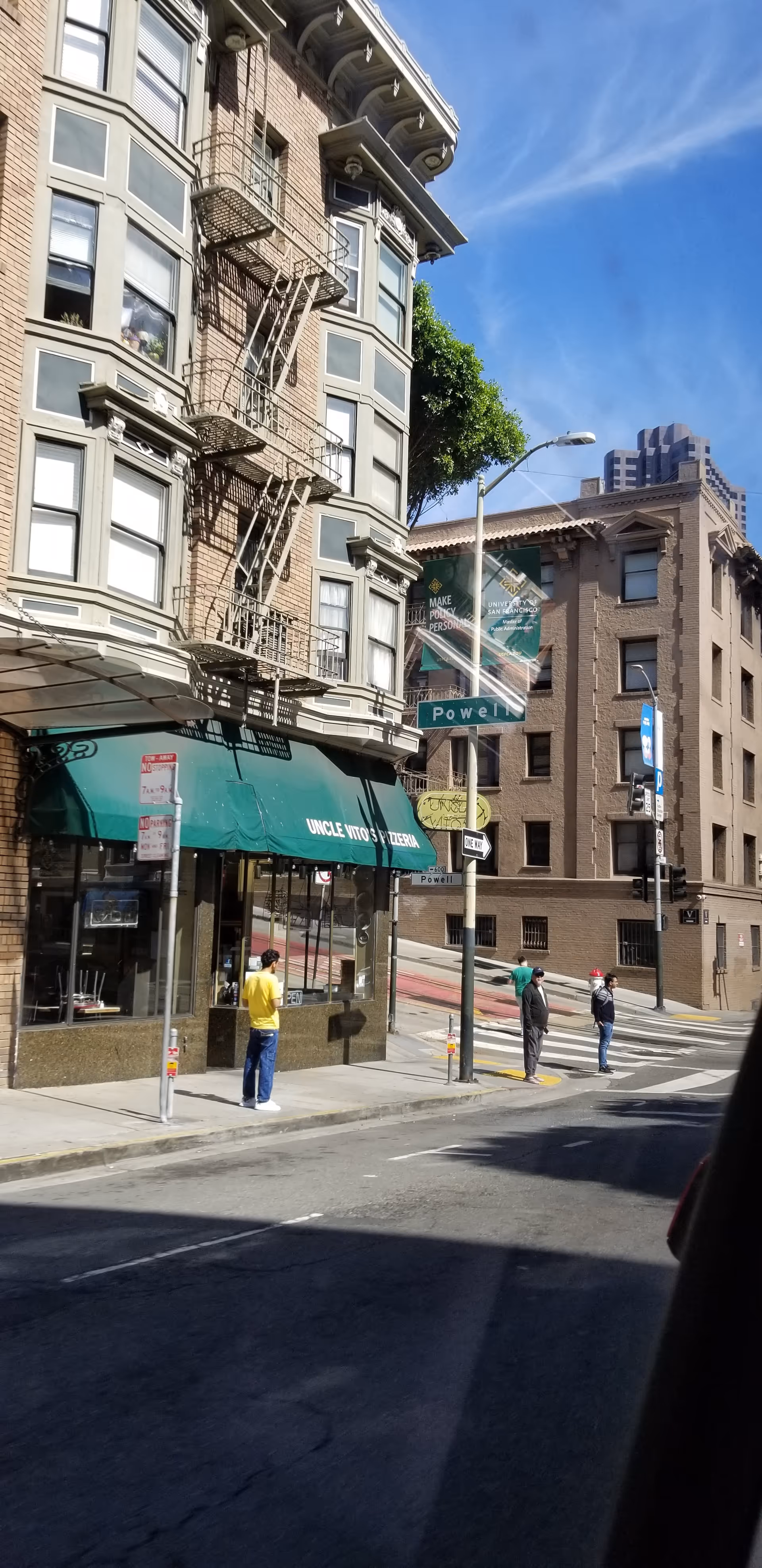 Urban San Francisco street scene with brick building, fire escapes, and pedestrians.