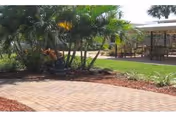 Outdoor walkway with brick path, landscaping, and a shaded seating area.