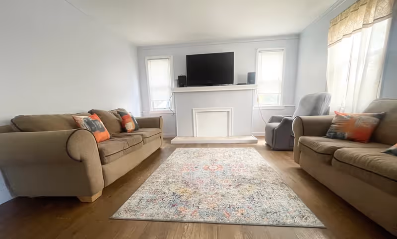 Cozy living room with beige sofas, a TV on the mantle, and a rug.