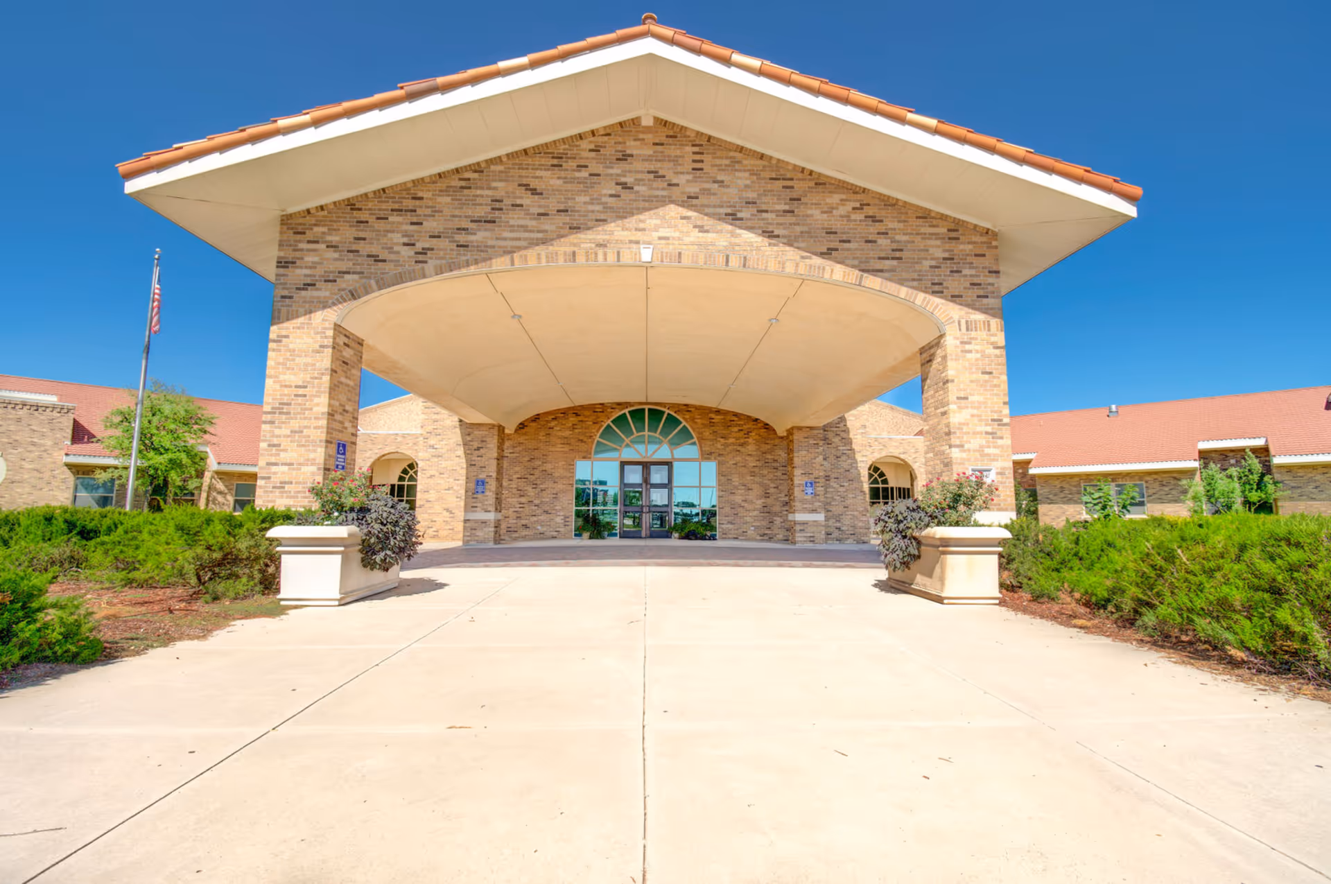The front entrance of a brick senior care center features a large covered drop-off area.