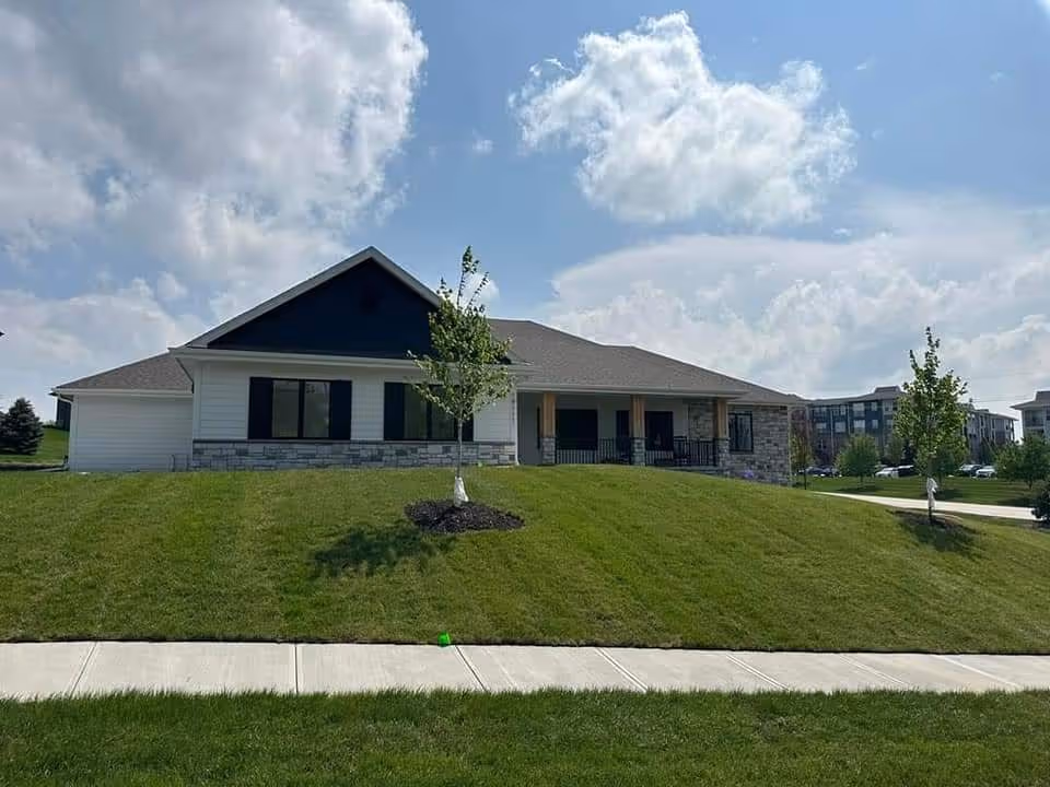 Single-story senior living facility with stone accents, front lawn, and sidewalk.