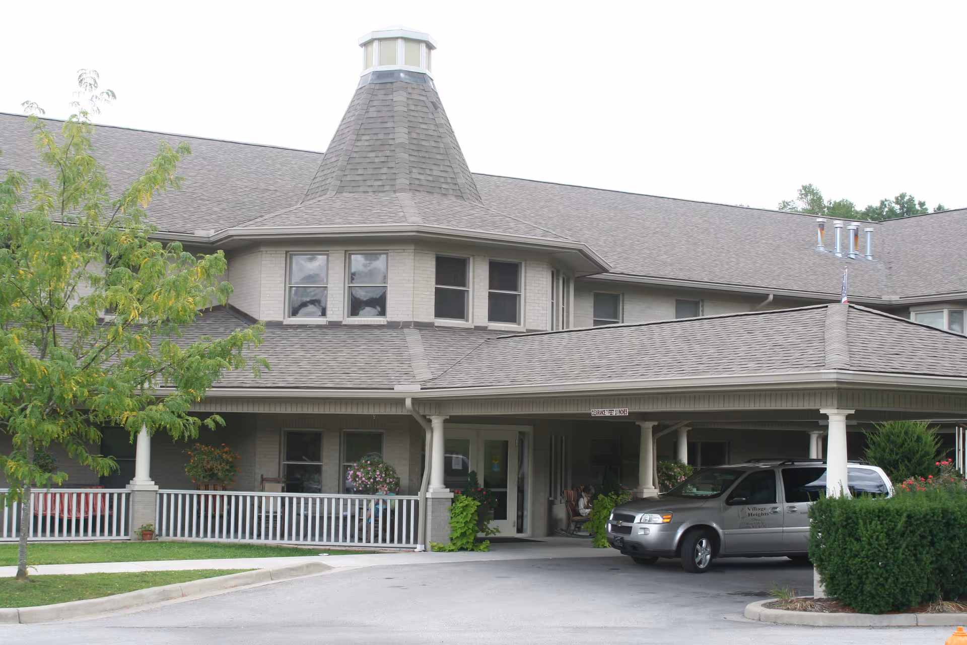 Village Heights senior living facility exterior with a covered entrance and a parked van.