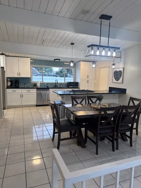 Bright open kitchen and dining area with a dark wood table and chairs.