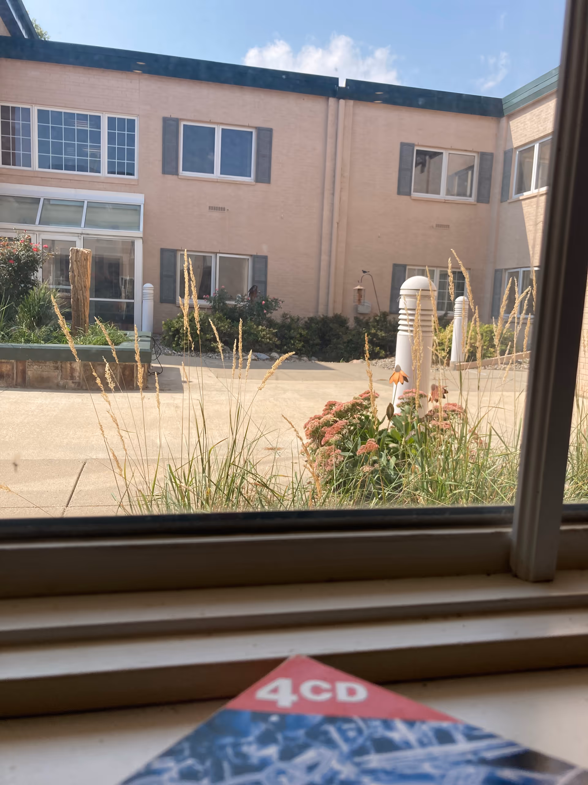 Exterior view of Crowell Memorial Home courtyard, beige brick building and garden plants.