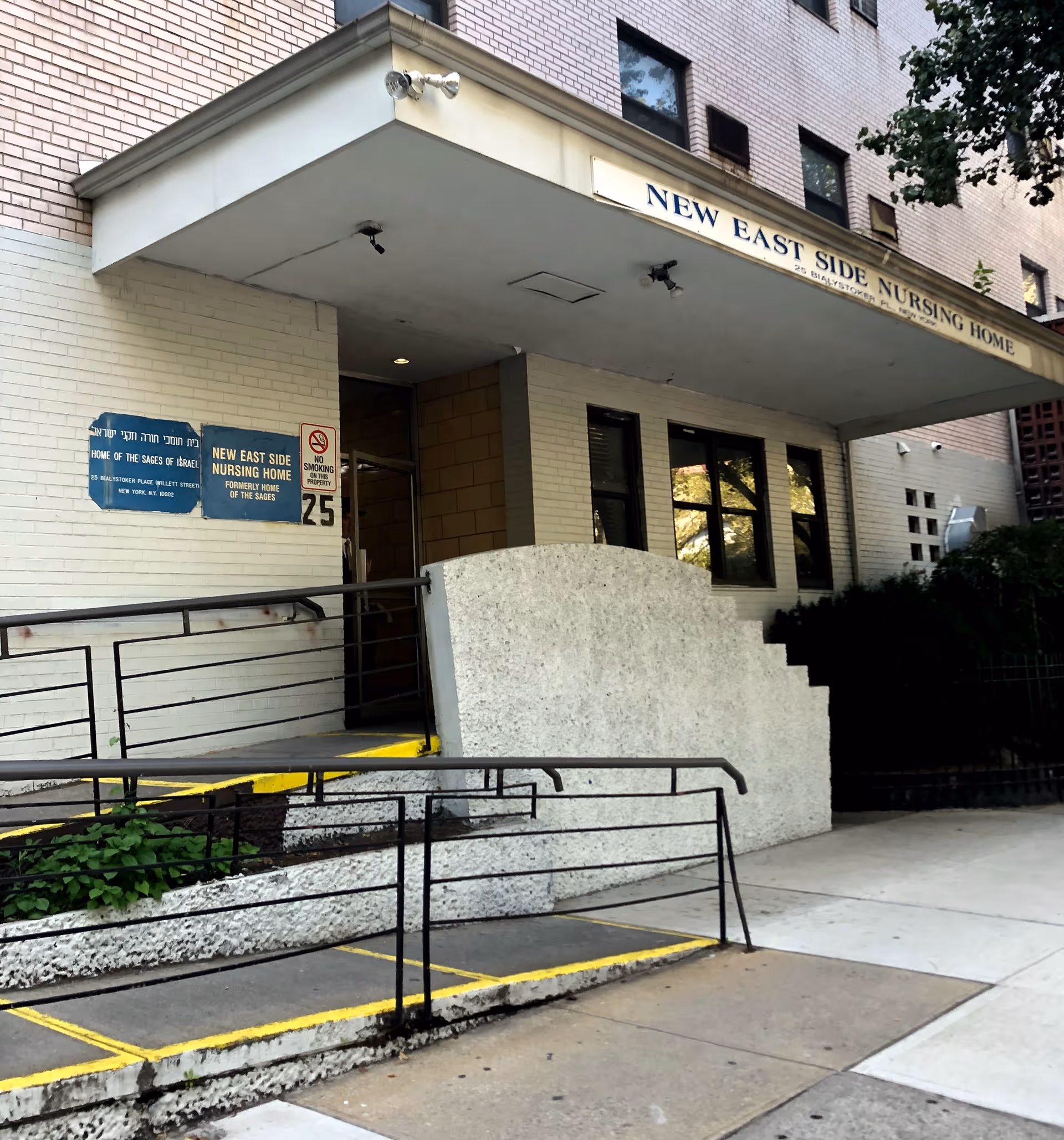 Front exterior of New East Side Nursing Home with stairs, ramp, and signage.