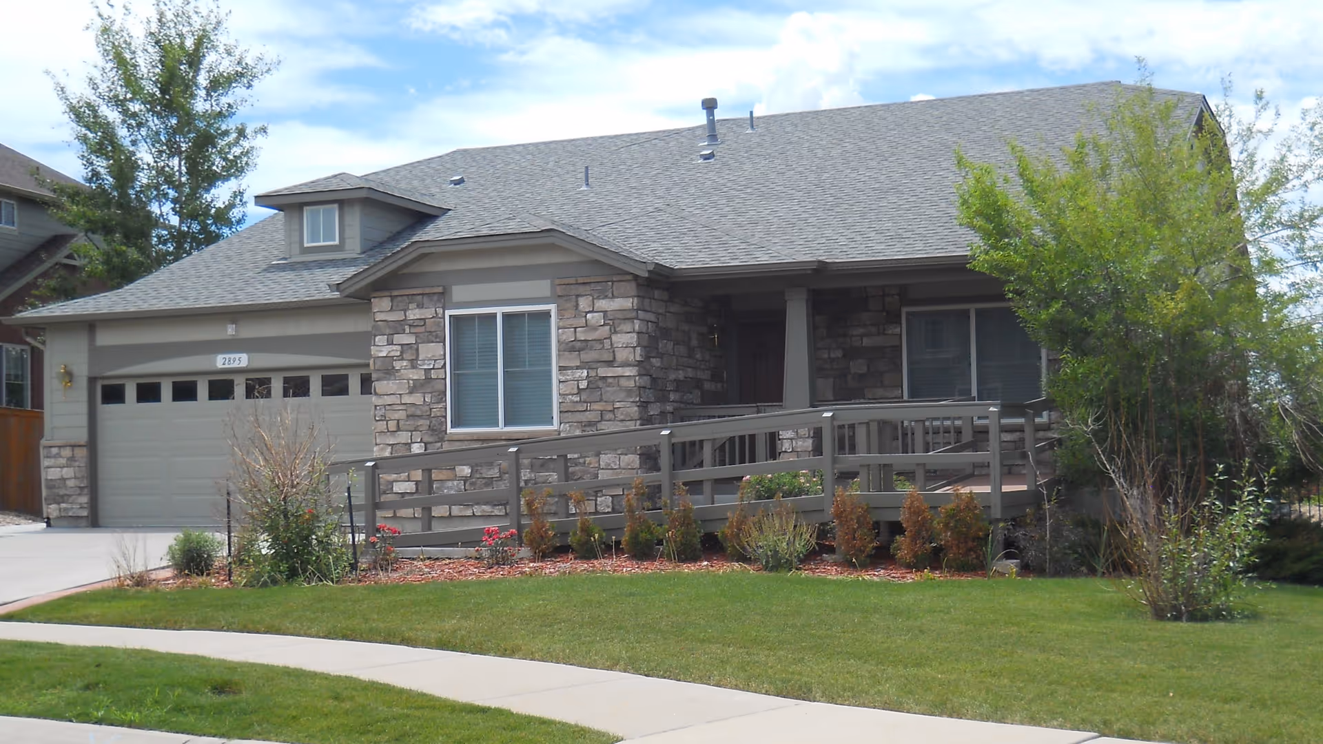 Front exterior view of Cardan Manor Assisted Living, a stone-facade house with ramp.
