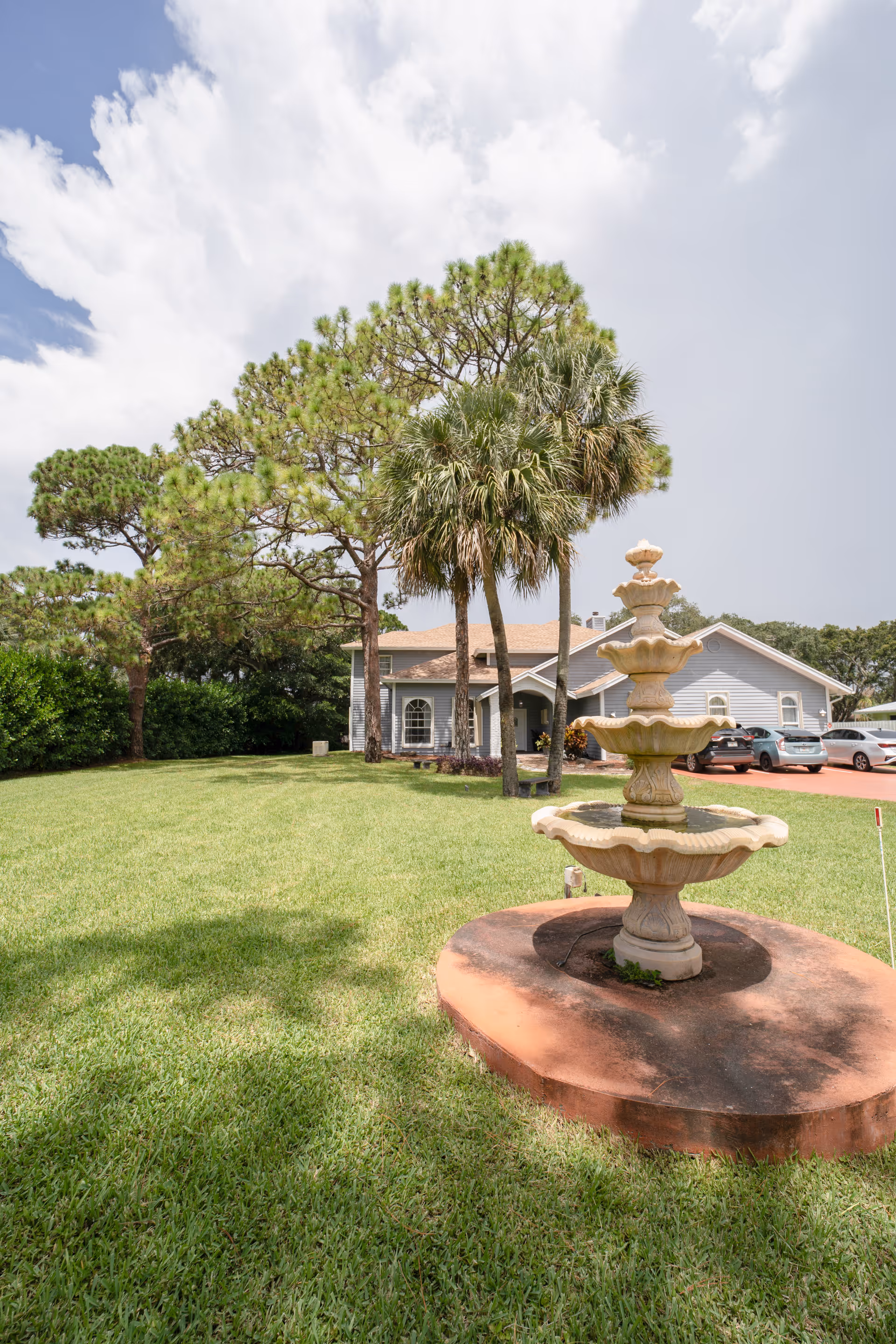Exterior view of Villa of Kings and Queens of Delray with a fountain and palm trees.
