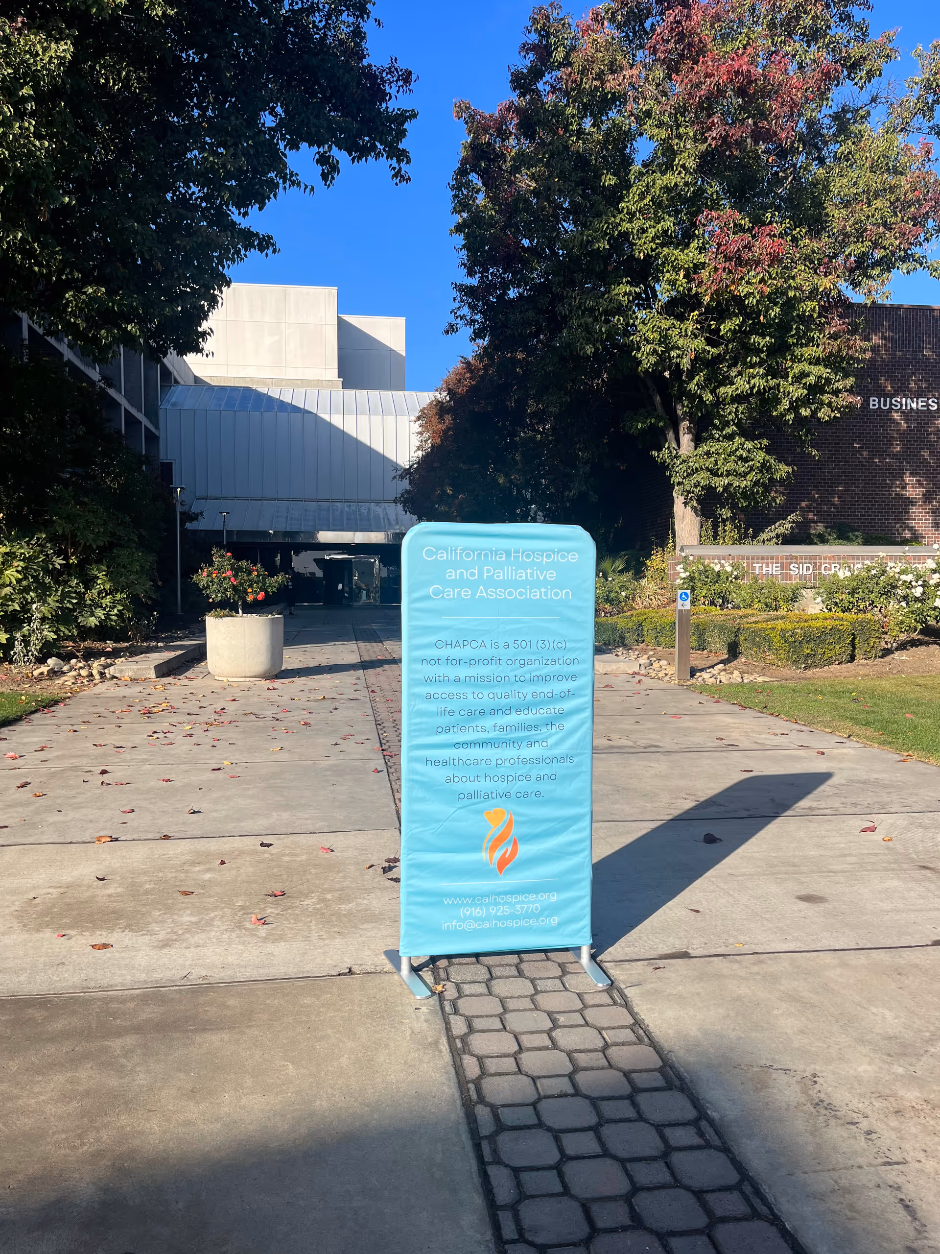 Blue CHAPCA banner stands on a sidewalk outside a modern building.