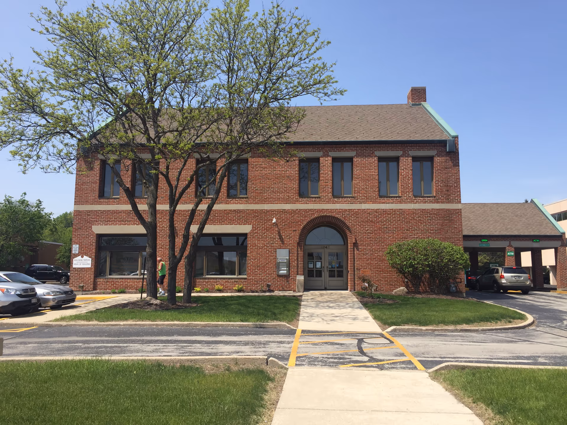 Two-story brick building with arched front entrance and a tree in front