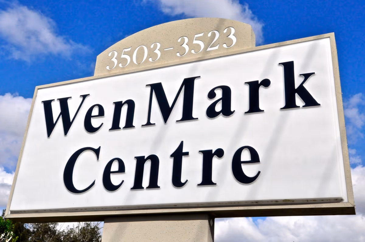 A large white exterior sign reading WenMark Centre against a blue sky.