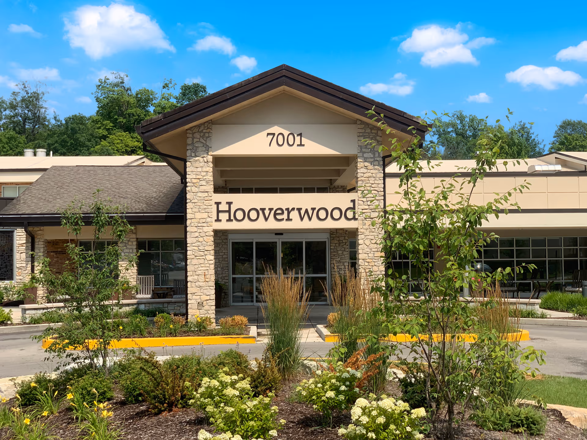 Hooverwood facility entrance with stone pillars, sign, and landscaped front garden.