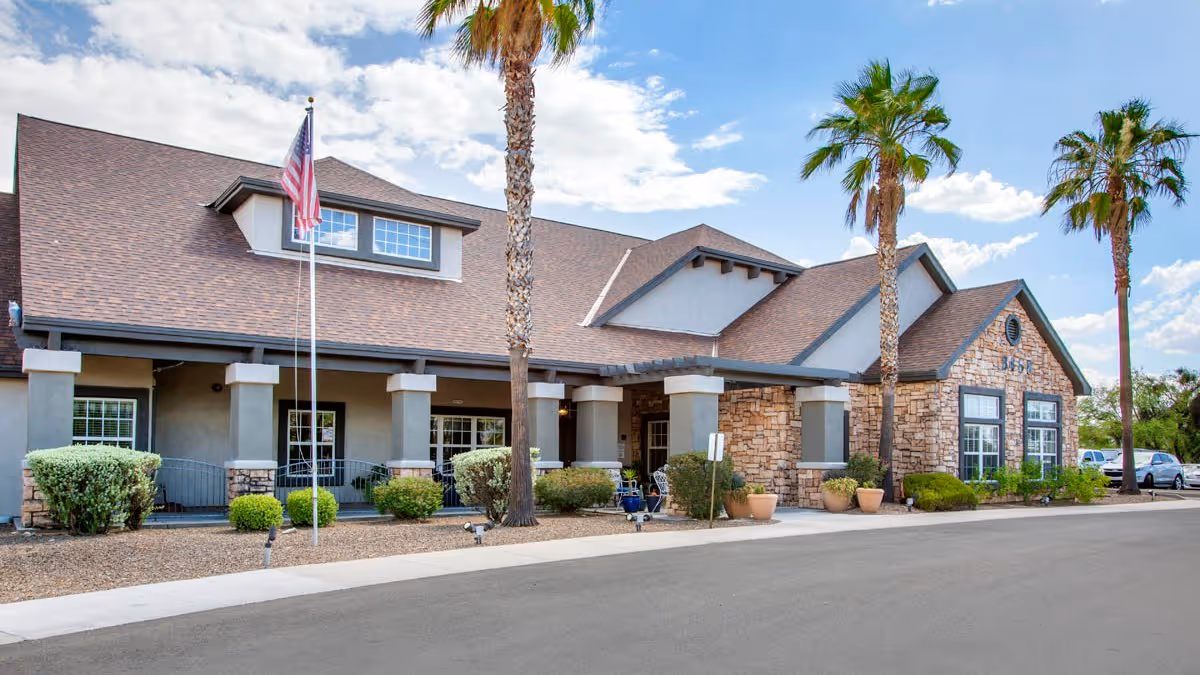 Brookdale East Tucson exterior with palm trees, flag, and front entrance.
