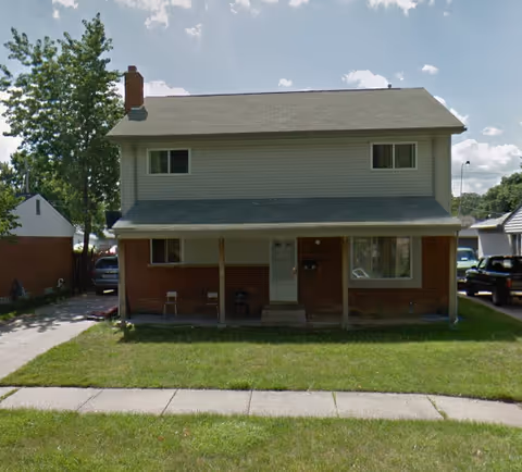 Two-story brick-and-siding building with a covered front porch and green lawn.