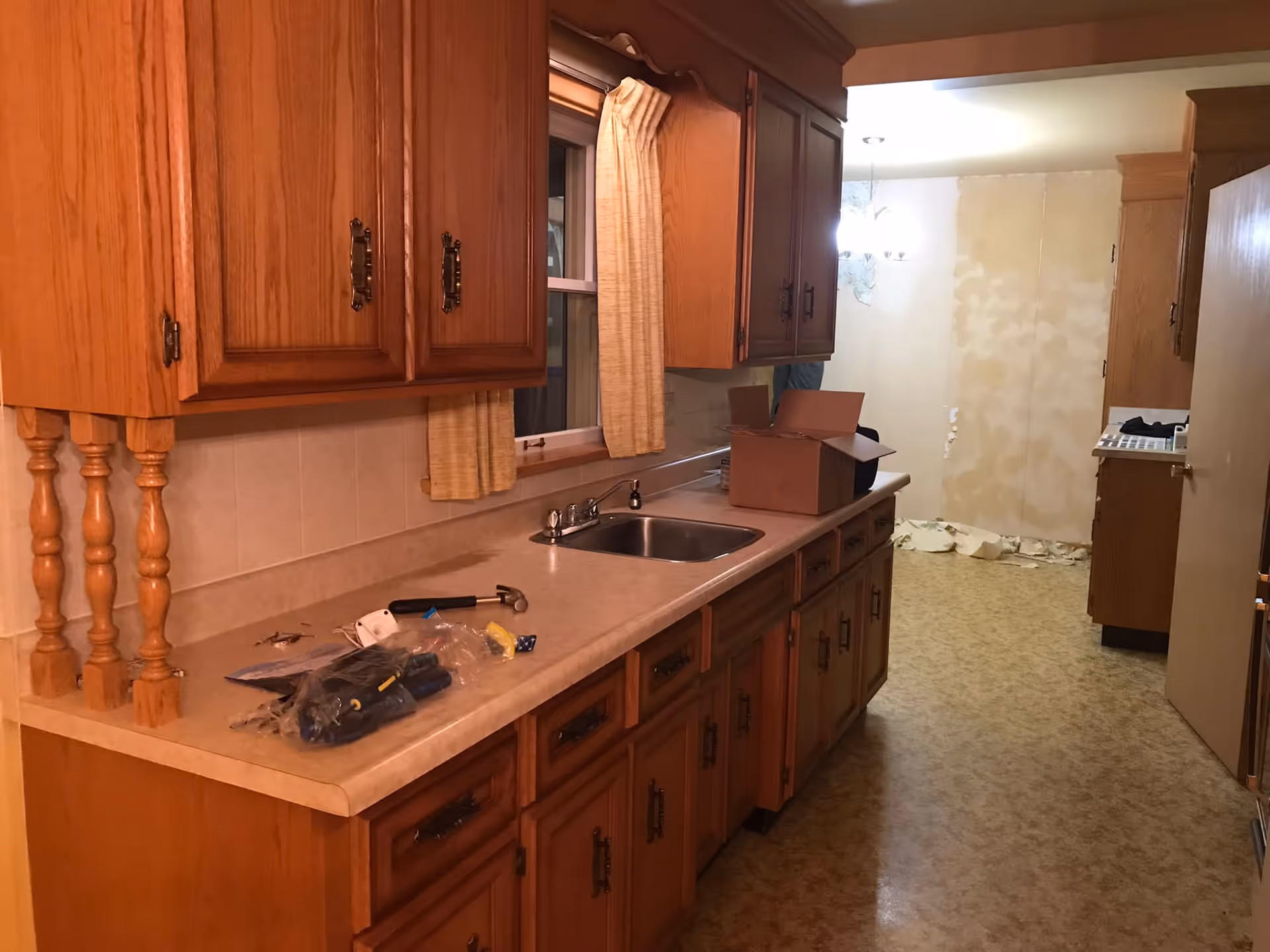 A kitchen with wooden cabinets, countertop, sink, and packing boxes.