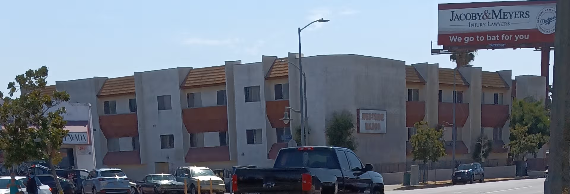 Exterior view of Westside Manor senior living building with parked cars.