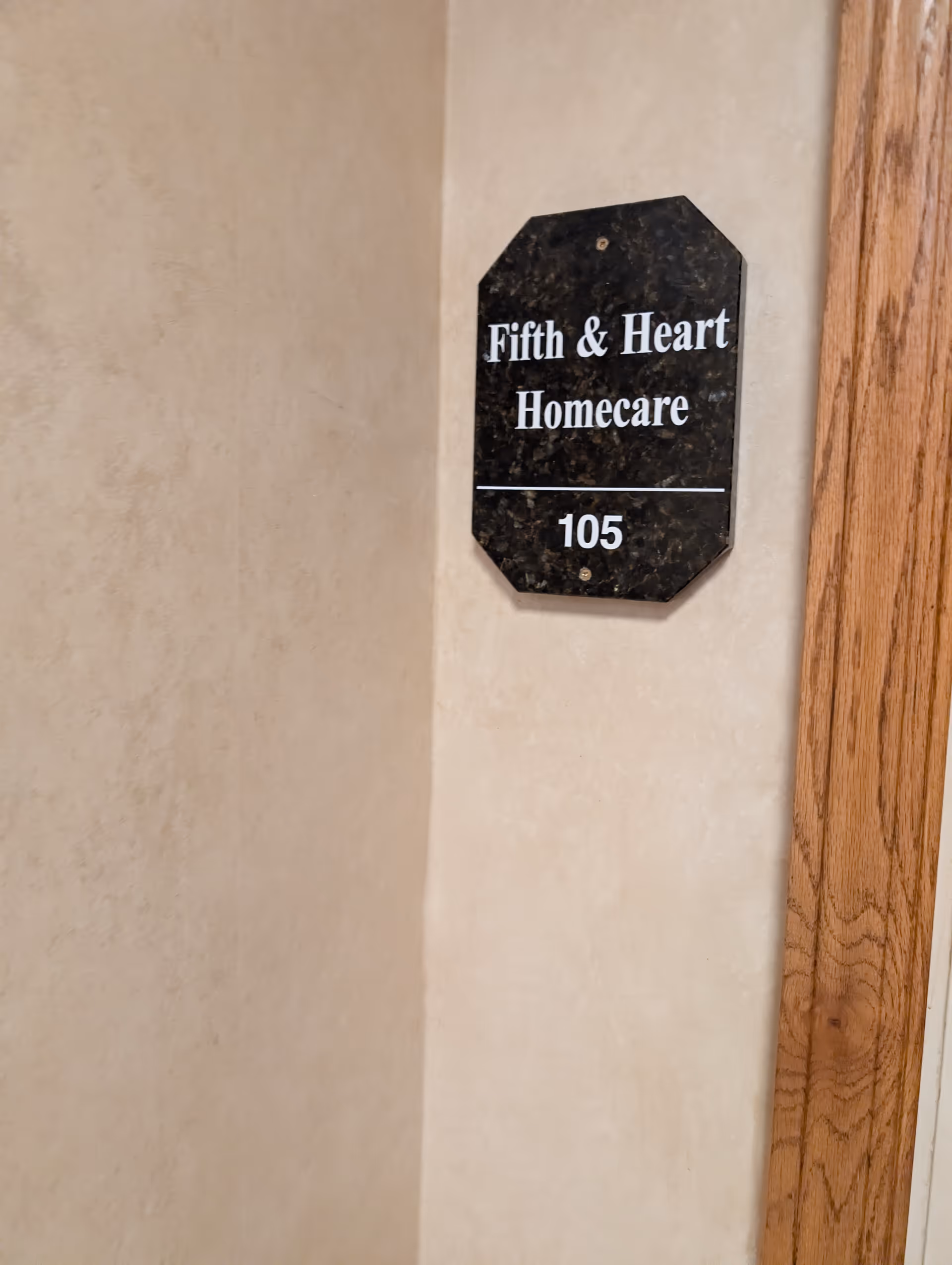 Interior hallway wall with a black sign reading Fifth & Heart Homecare, 105.