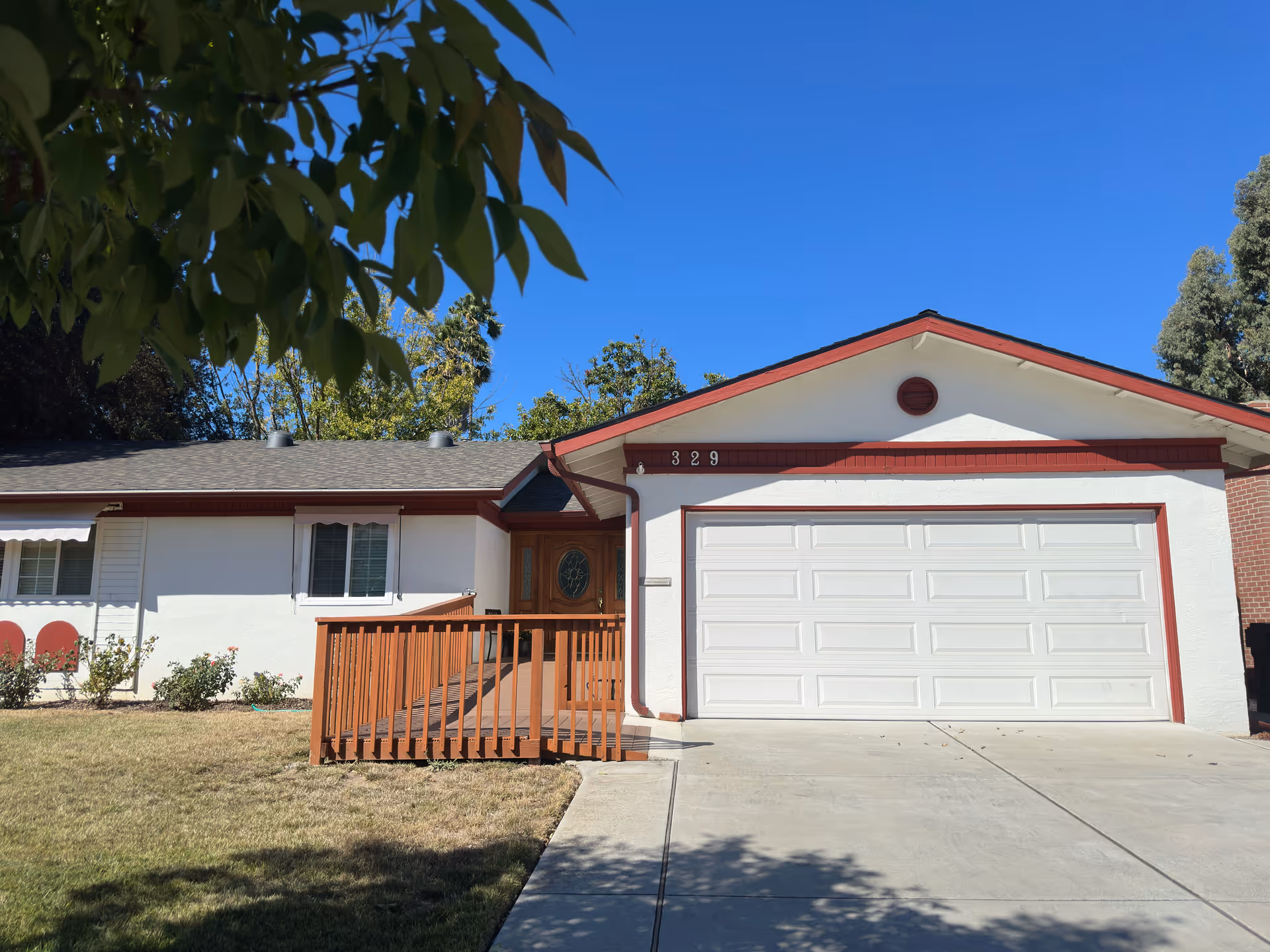 Exterior of a single-story care home with white walls, red trim, and a two-car garage.