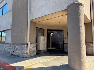 Entrance to a senior living facility with glass doors, columns, and stone accents.