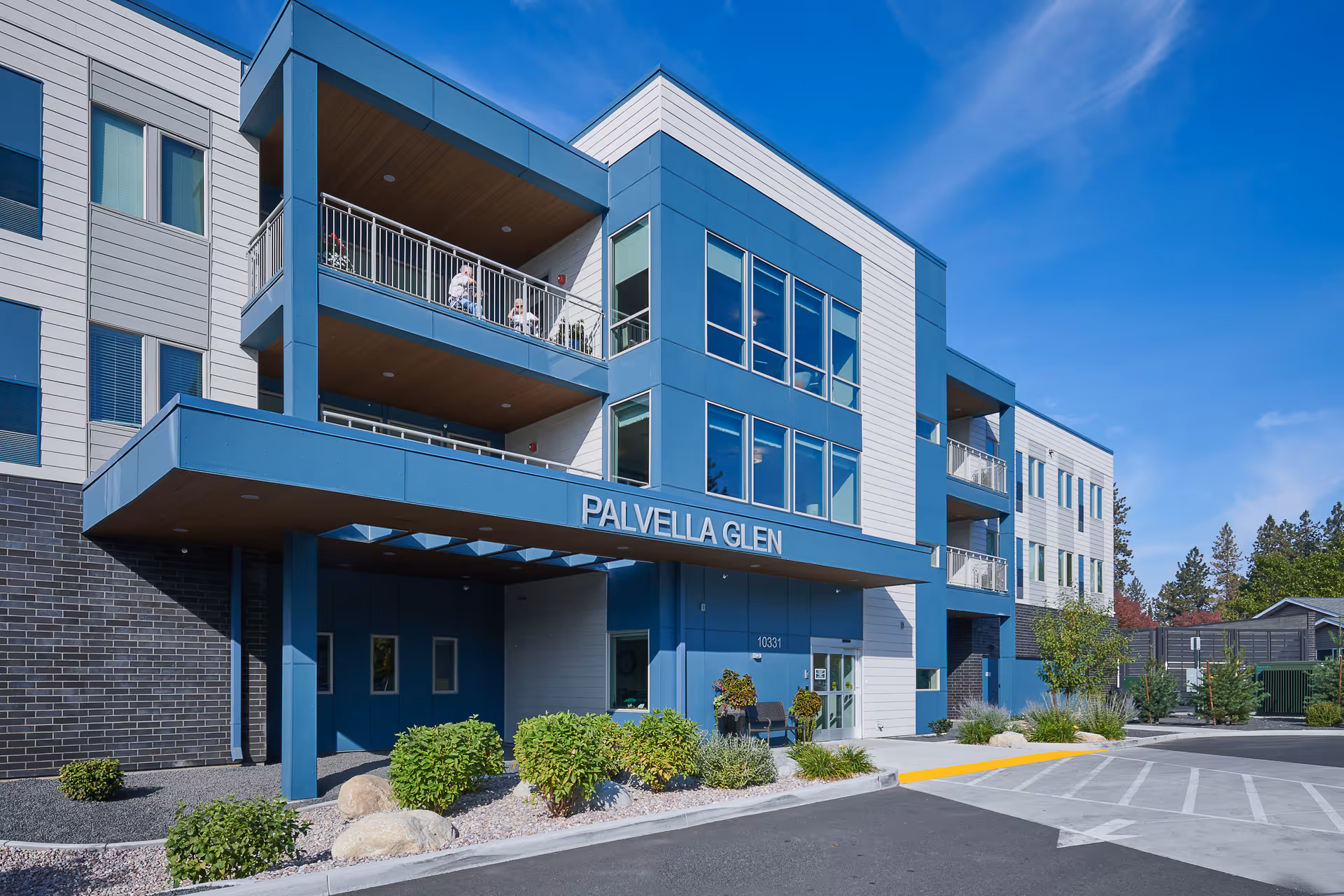 Front facade of a modern senior living residence with balconies and landscaped entrance.