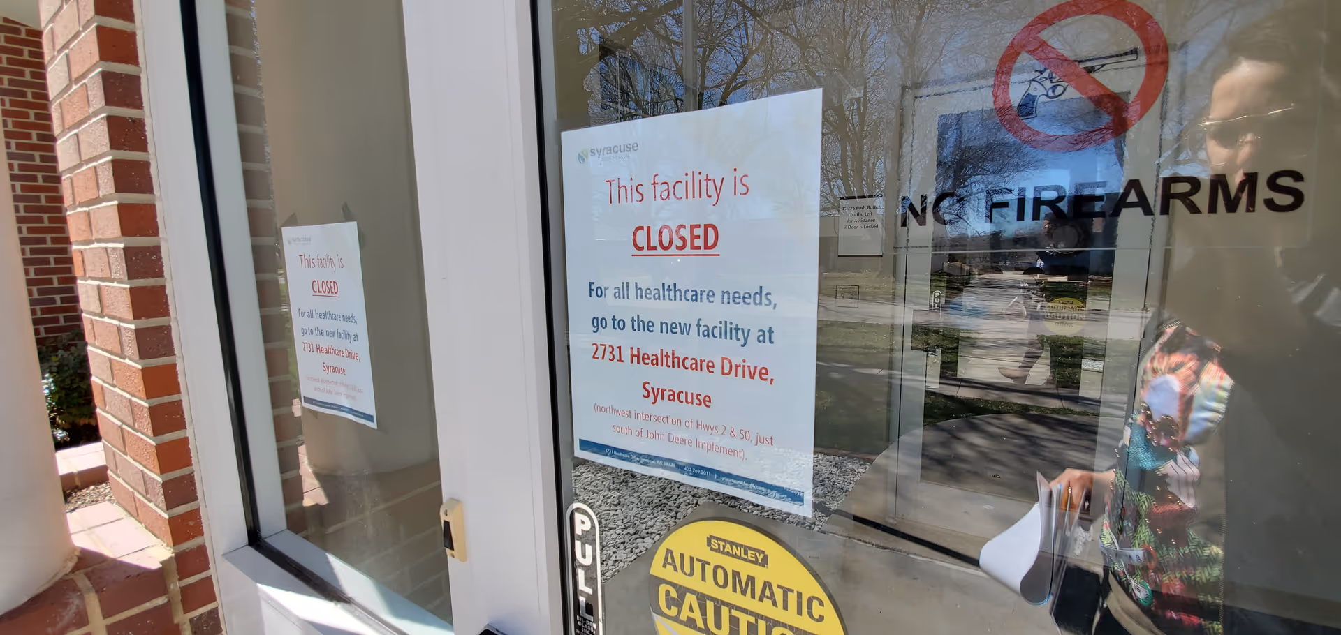 Glass storefront with 'This facility is CLOSED' sign and a reflected person at the entrance.
