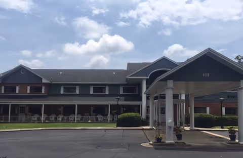 Front exterior of a senior living facility with a covered entrance and parking.